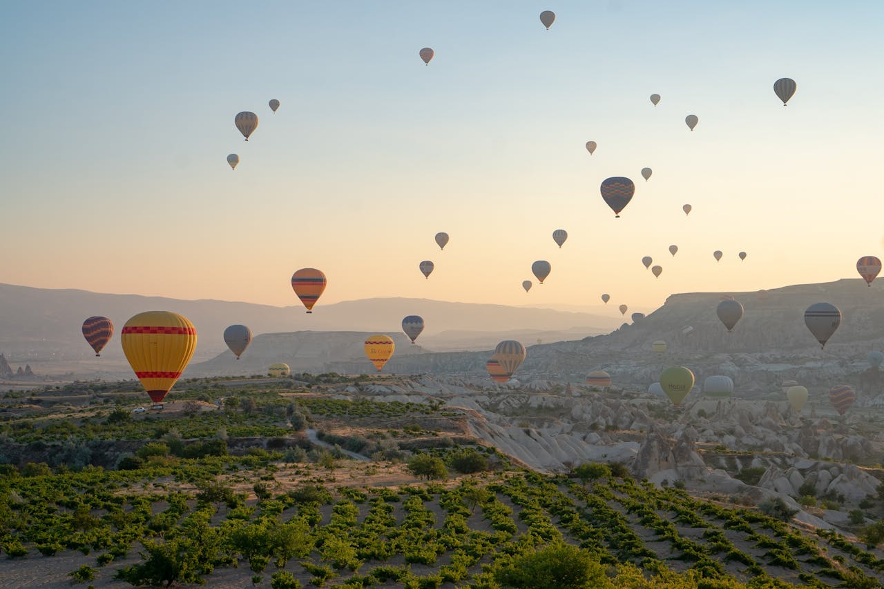gallery-01 Stunning view of hot air balloons flying above Cappadocia's landscape at sunrise.