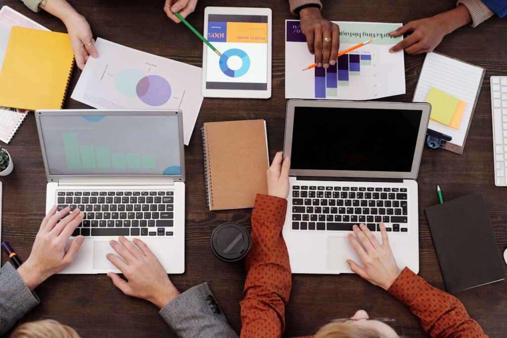 pexels photo 6476258 Overhead view of a team discussing digital marketing strategies with laptops and charts.